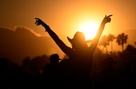 The Coachella festival grounds at sunset, with crowds and art installations.