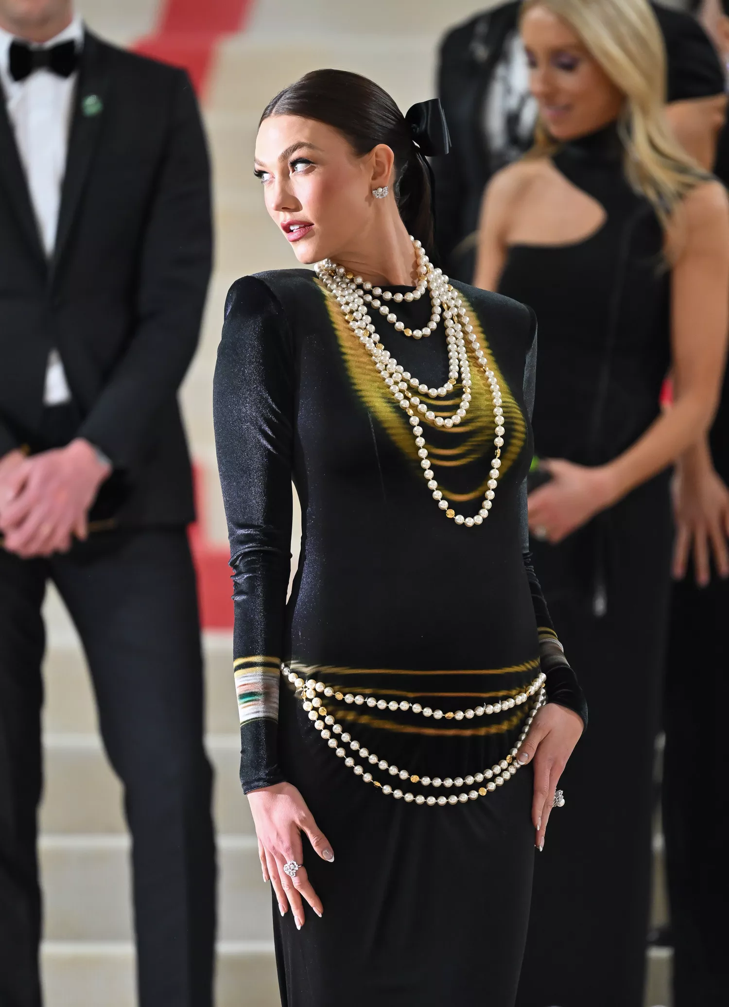 Karlie Kloss at the 2025 Met Gala in a stunning black dress, cradling her baby bump