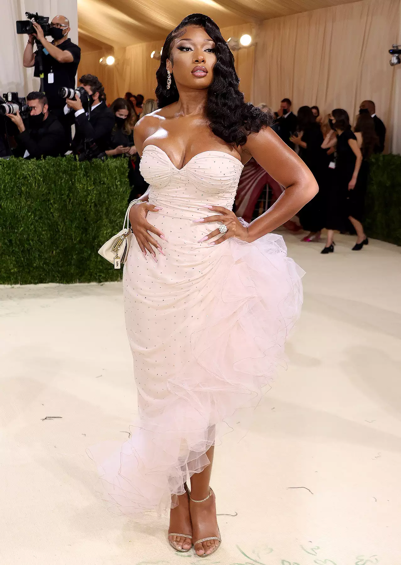 Megan Thee Stallion at the 2025 Met Gala in a gleaming silver sequin gown with an extravagant white coat, embodying red carpet elegance.