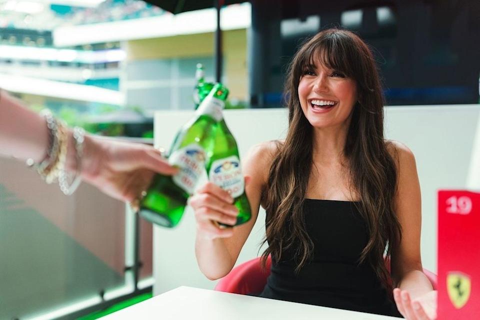 Nina Dobrev smiling at an F1 event, showcasing her signature style