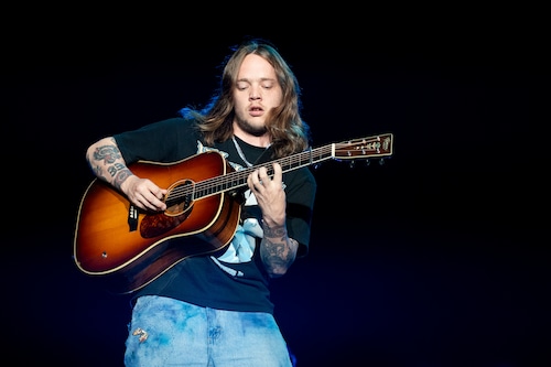 Billy Strings playing guitar on stage.