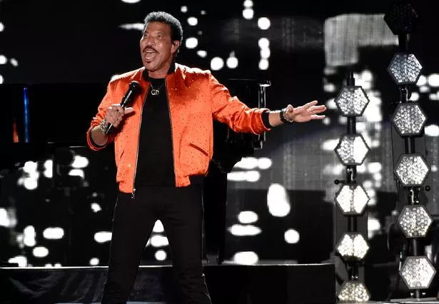Lionel Richie performing live on stage, engaging with his enthusiastic fans.