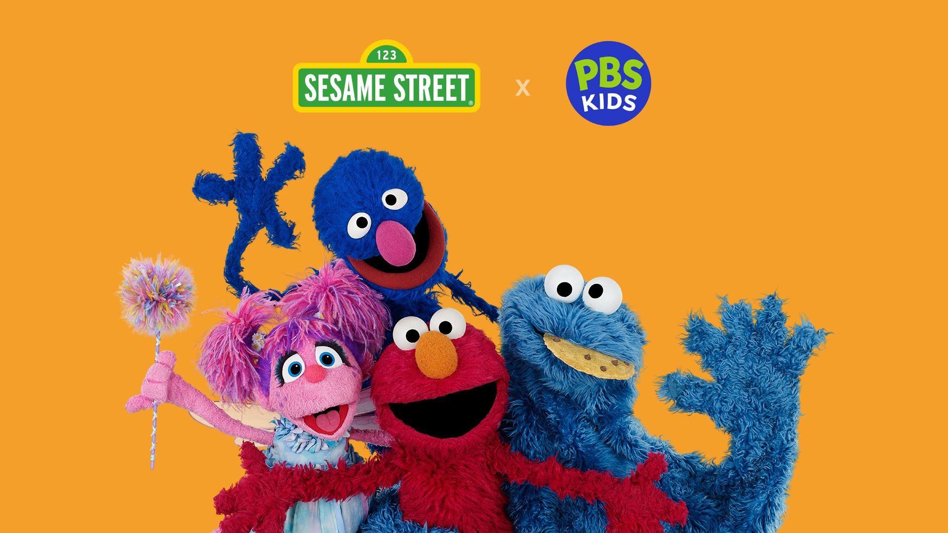 Colorful cast of Sesame Street characters smiling on set